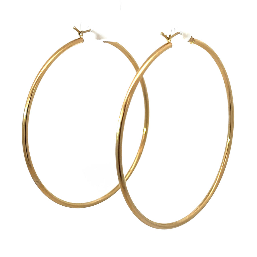 Pair of bold 14k gold 60mm hoop earrings displayed on white background