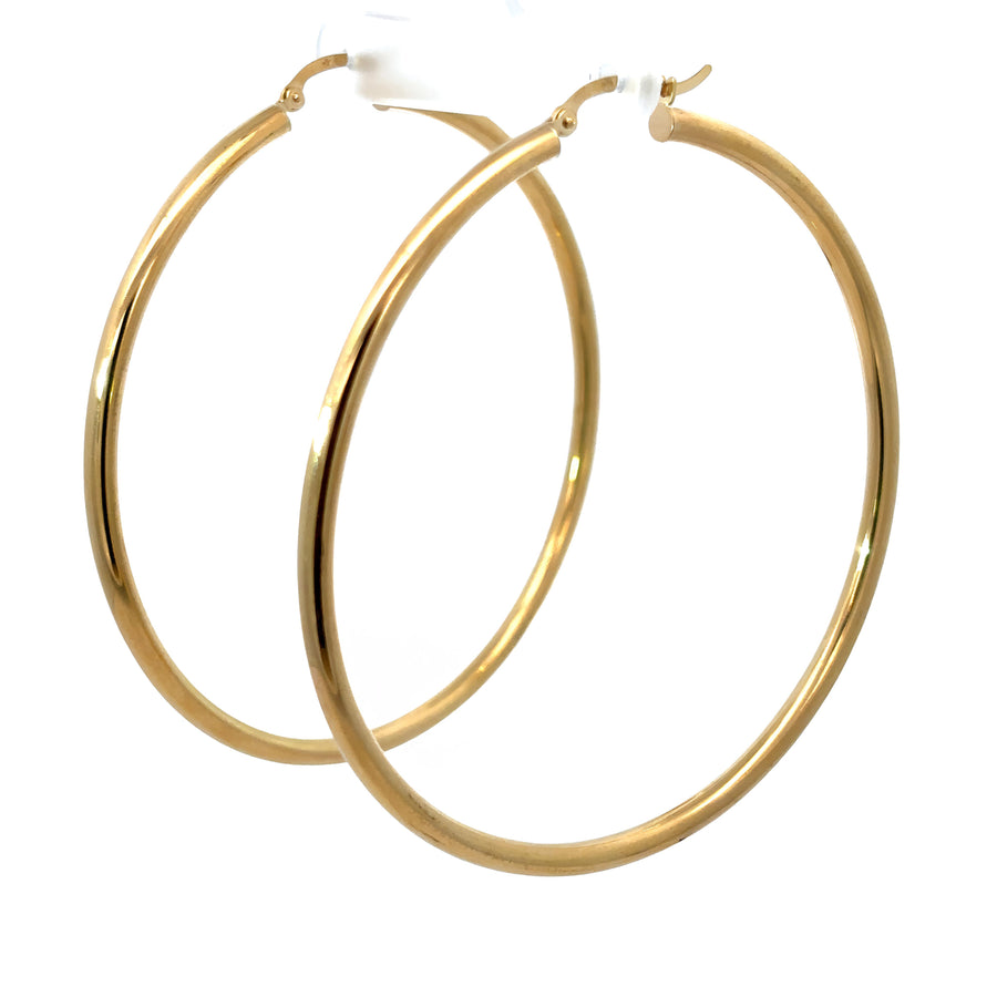 Woman wearing bold 14k gold 65mm hoop earrings