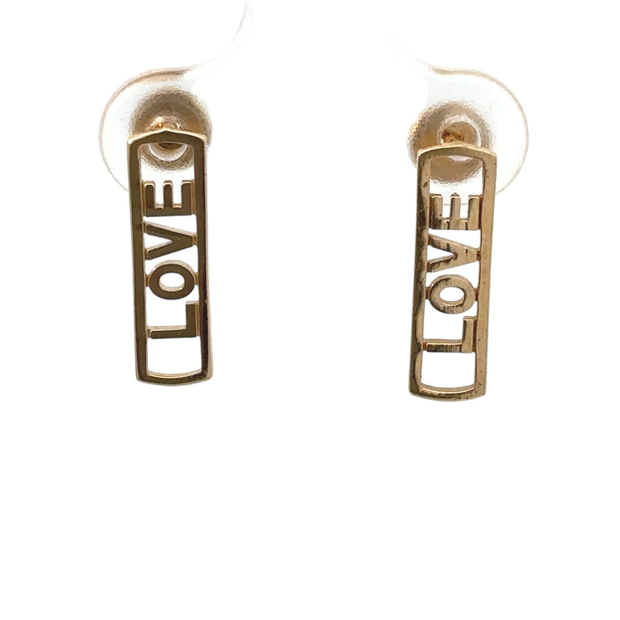 Close-up of baby earrings featuring “love” motif in gold