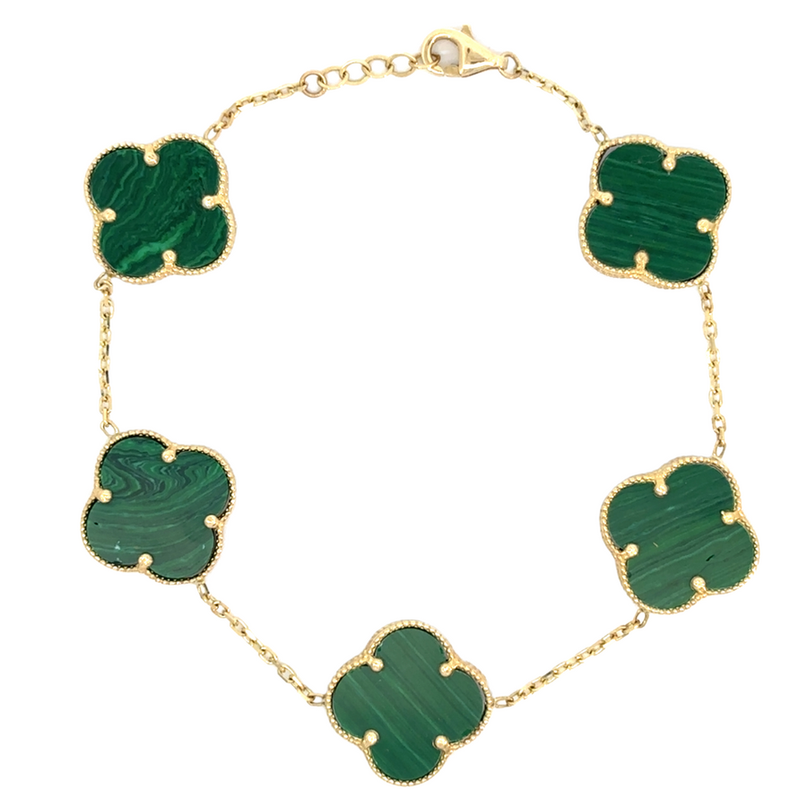 Flat-lay of 14k gold bracelet with five green accents on white background