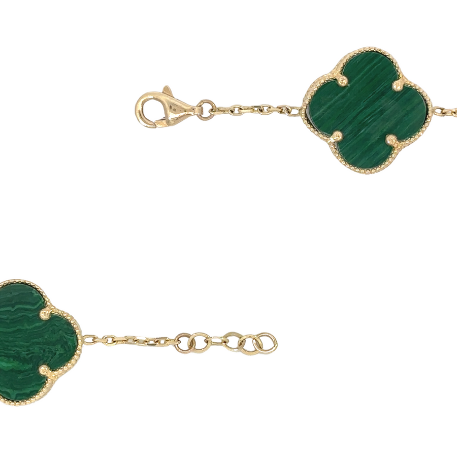 Woman wearing 14k gold bracelet with green accents on wrist