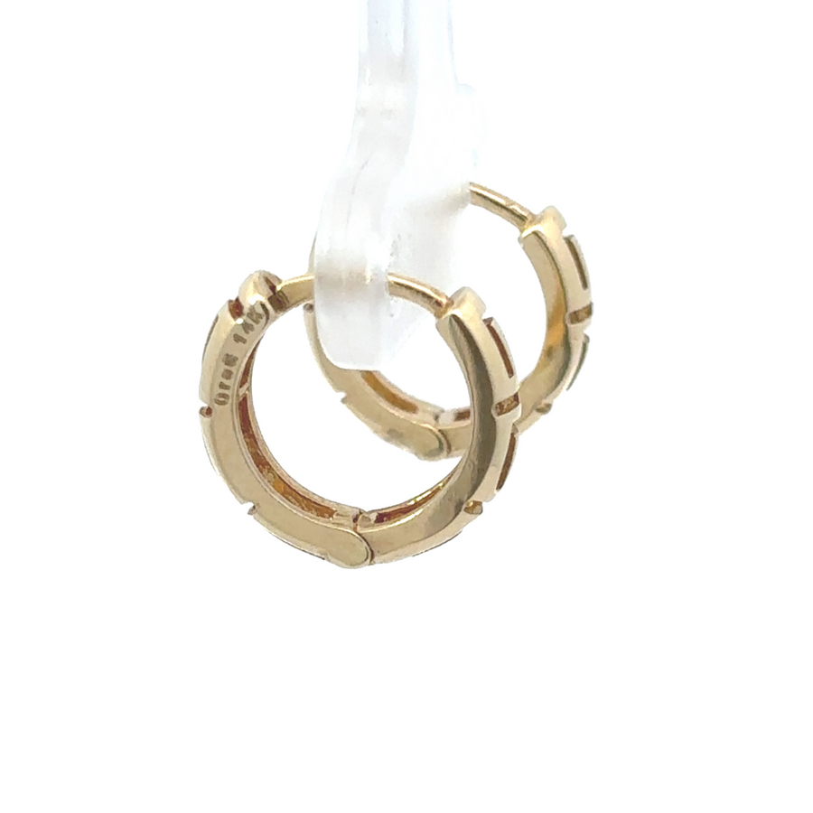 Woman styling 14k gold earrings, enhancing a chic and timeless look