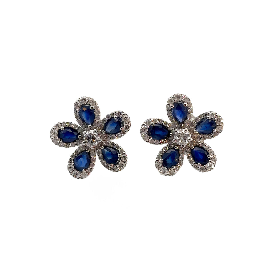 Close-up of floral earrings featuring diamonds and deep blue sapphire