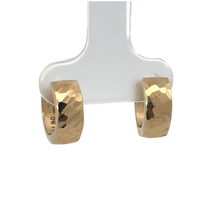 Close-up of faceted texture on small gold huggie earrings