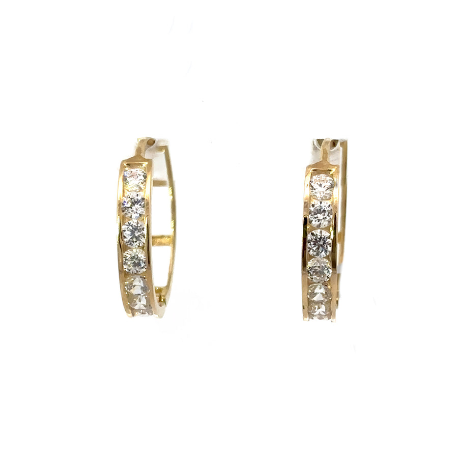 Minimalist gold huggie earrings resting on white background