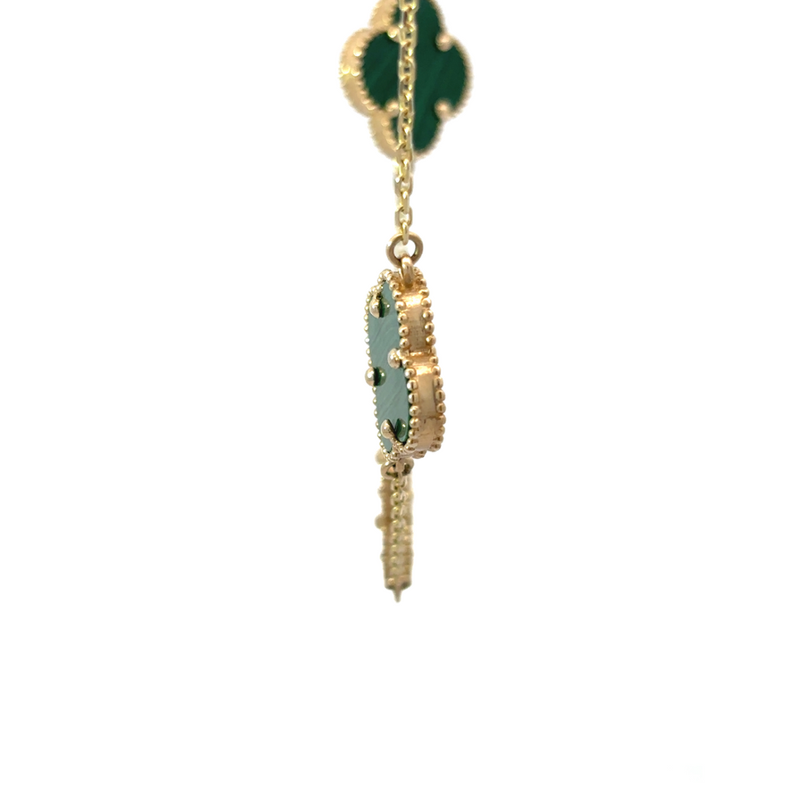 Woman wearing 14k gold necklace with ten green details layered with other pieces