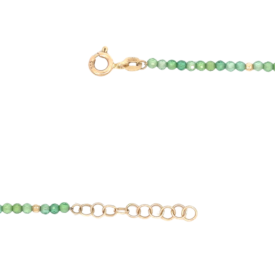Woman wearing 14k gold necklace with green stone