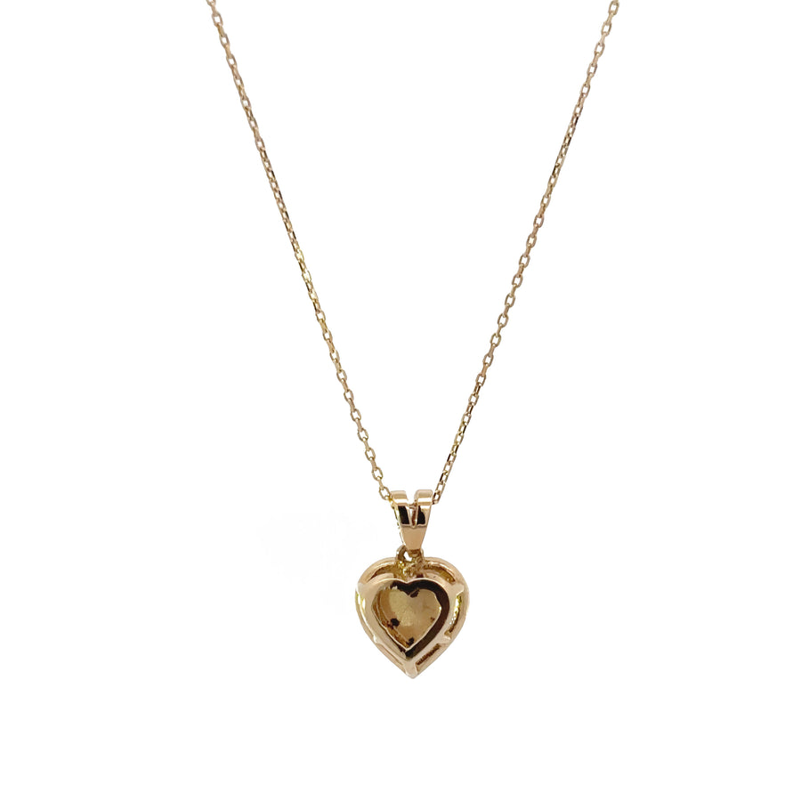 Close-up of heart and diamond charm on fine gold chain