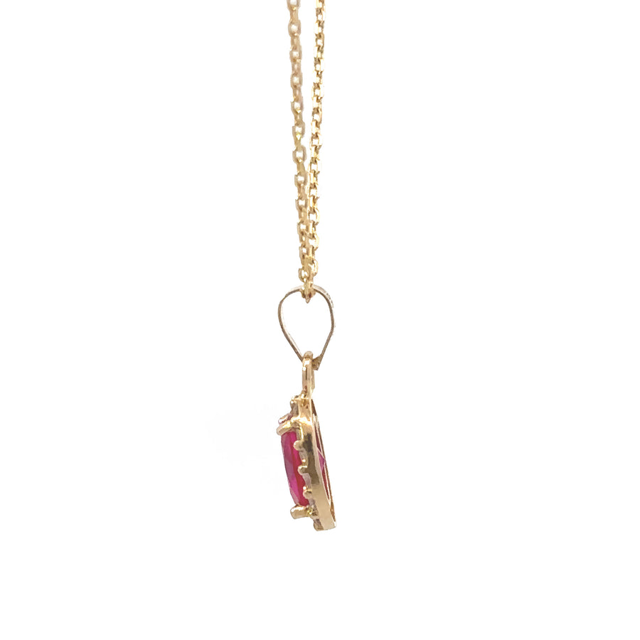 Small oval pendant in 14k gold resting on neutral background