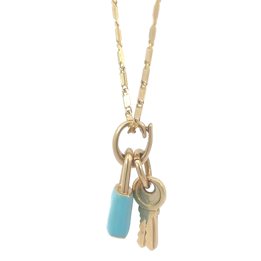 Elegant woman wearing 14k gold pendant with blue enamel and gold keys