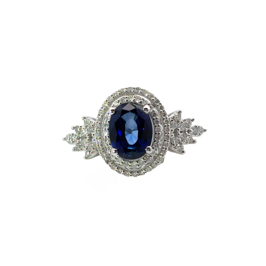Ring displayed on white background showcasing diamonds and sapphire