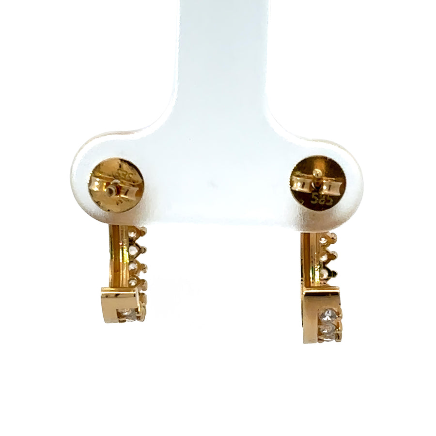 Baby wearing small gold hoop earrings with butterfly design