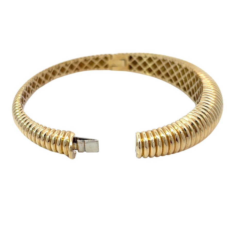 Stacked gold bangles featuring wide solid line bangle