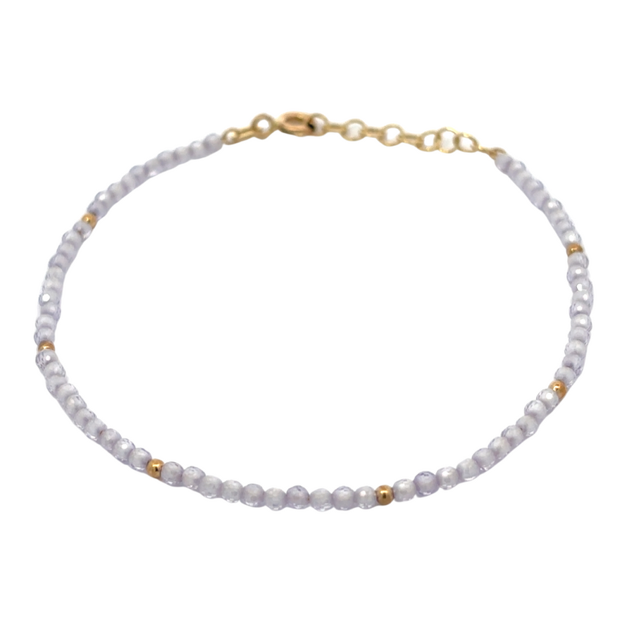 Elegant woman wearing 14k gold bracelet with pastel lila accents
