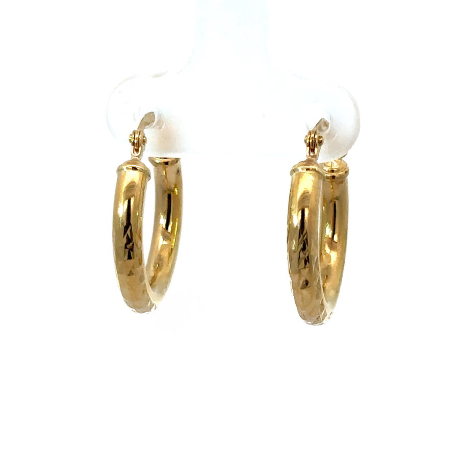 Close-up of 14k gold XS faceted huggies earrings for women