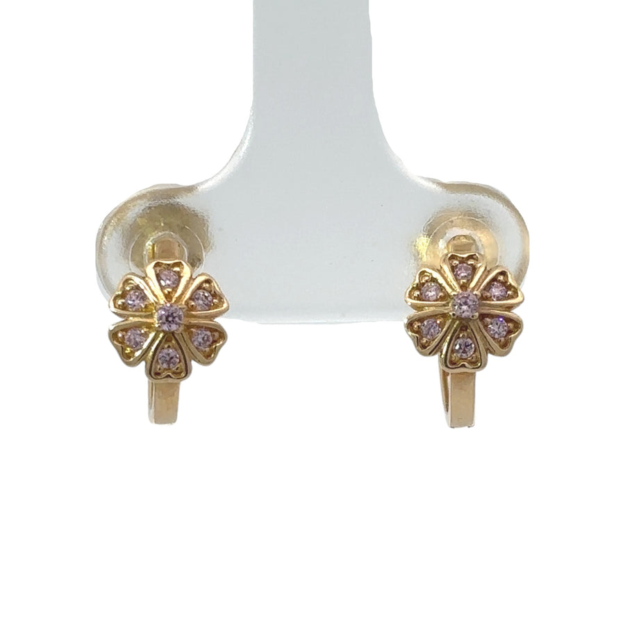 Close-up of XS gold huggie earrings featuring flower design