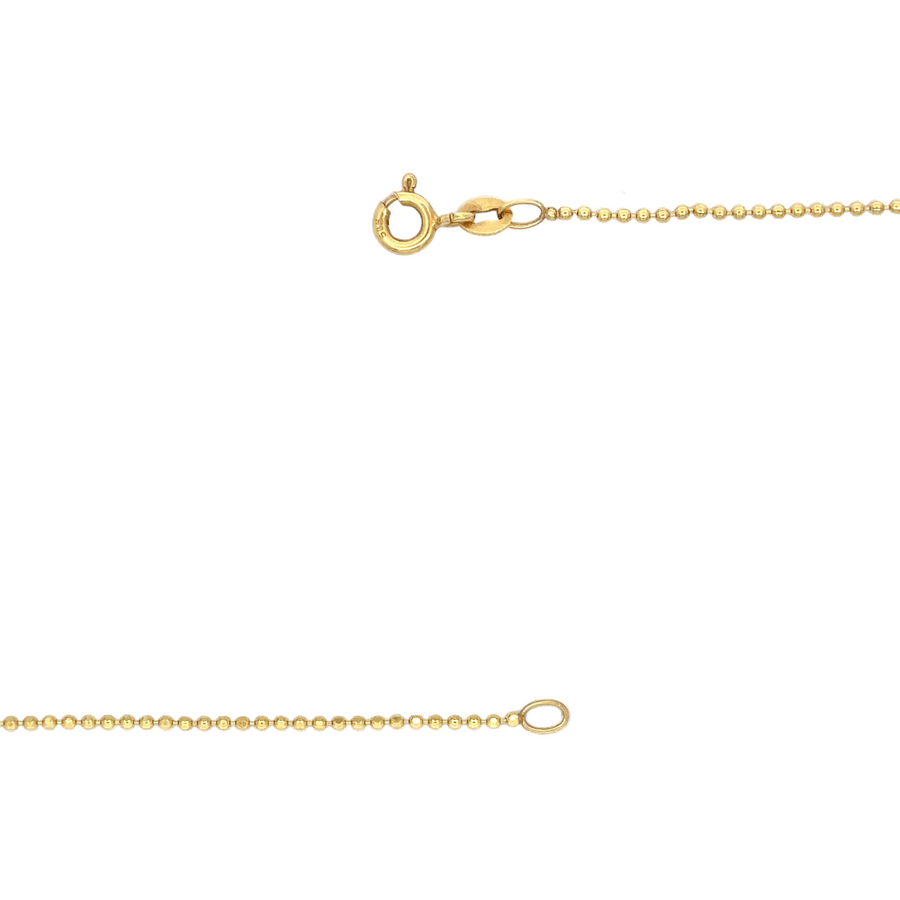 14k gold XXS ball chain necklace coiled on a neutral fabric surface