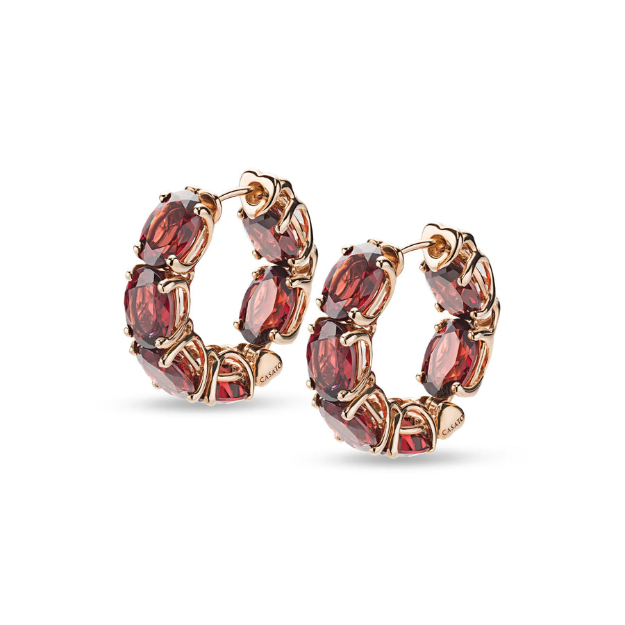 Close-up of 18K rose gold hoop earrings with garnet and diamond accents