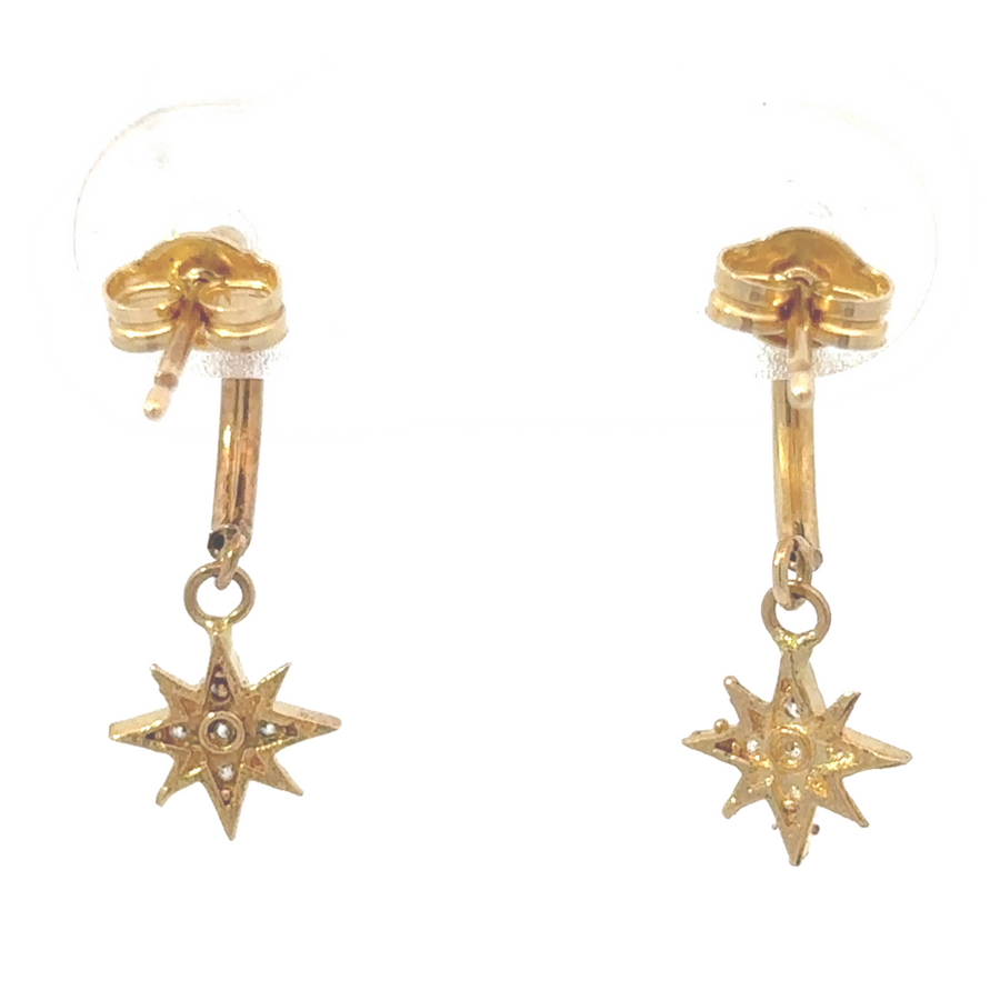 Flat lay of hoop earrings on soft fabric, emphasizing gold tone and charm detail