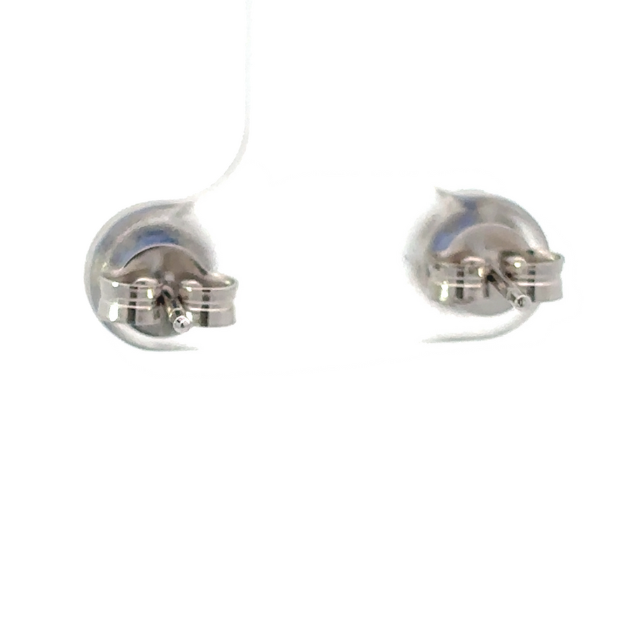 Woman wearing 18k gold earrings with striking blue center stones