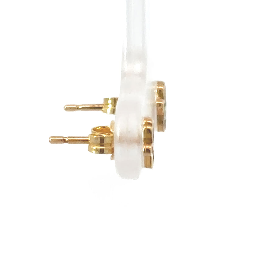 Tiny gold earrings displayed in a jewelry box