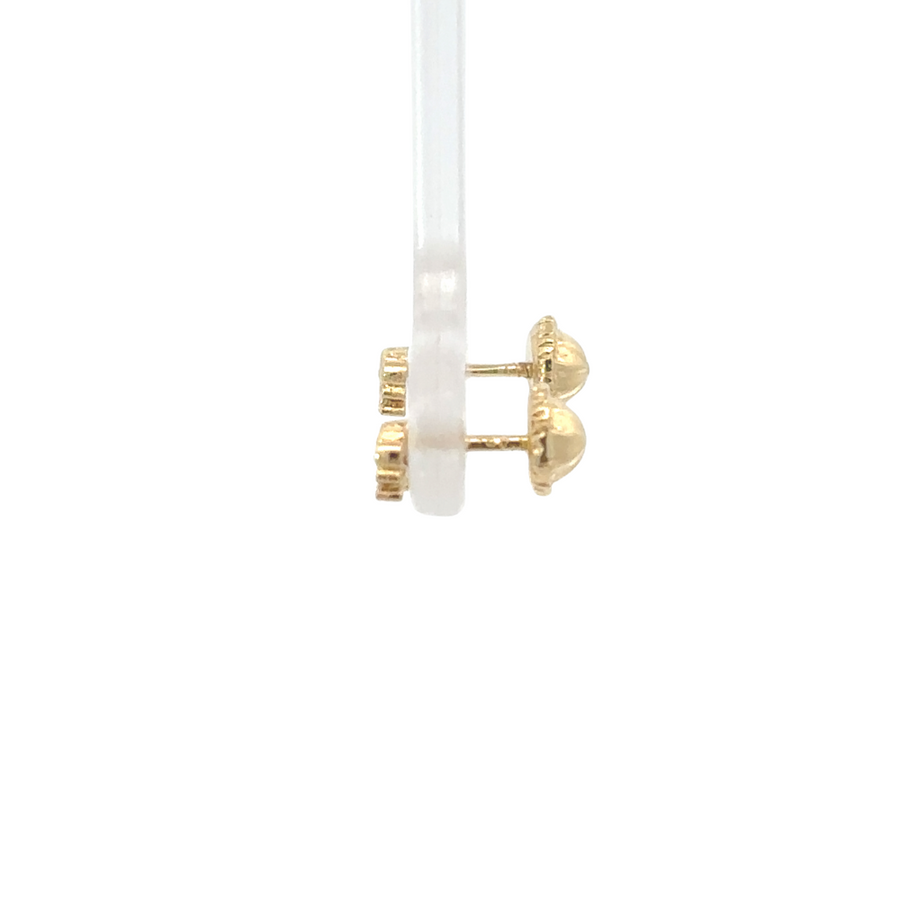 Woman wearing small crown-shaped stud earrings in gold