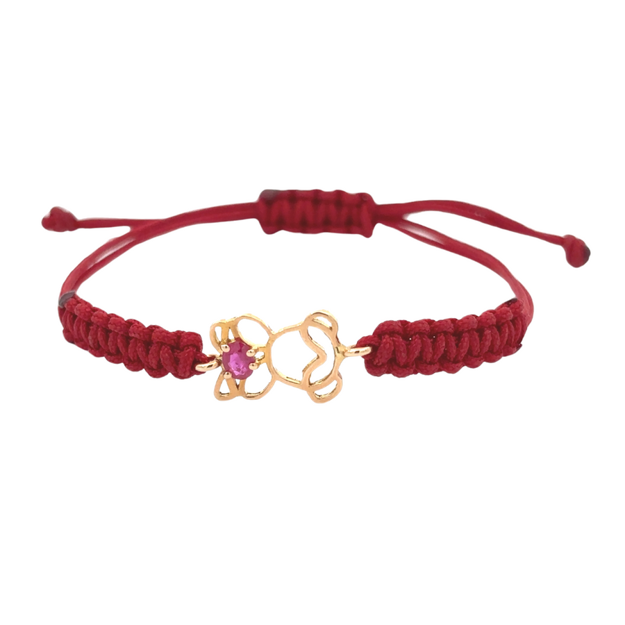 Close-up of 18k gold bracelet with red accent and girl charm on a white background.
