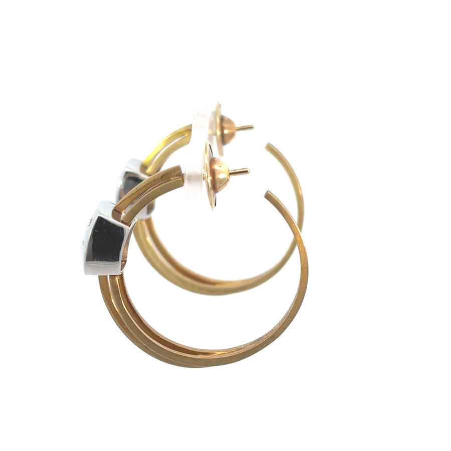 Pair of 18k gold diamond earrings displayed on white velvet