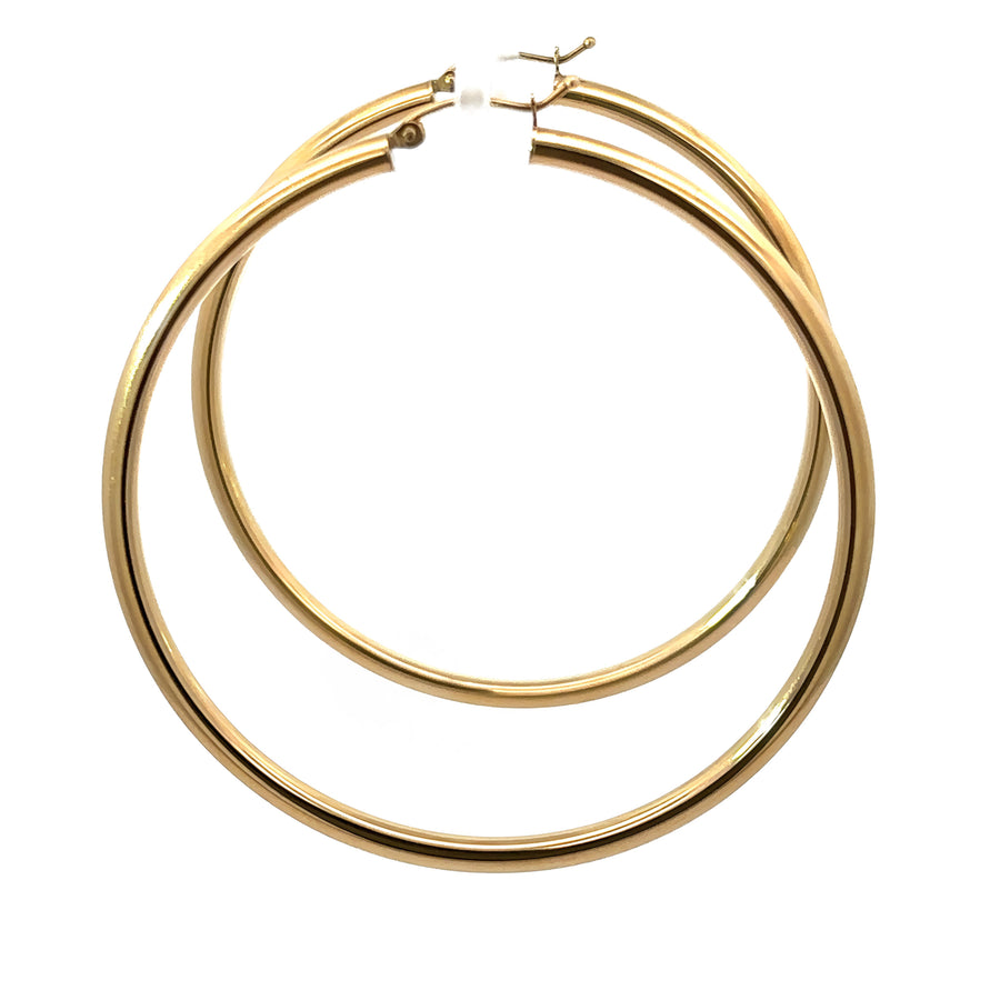 Woman wearing bold 14k gold 60mm hoop earrings