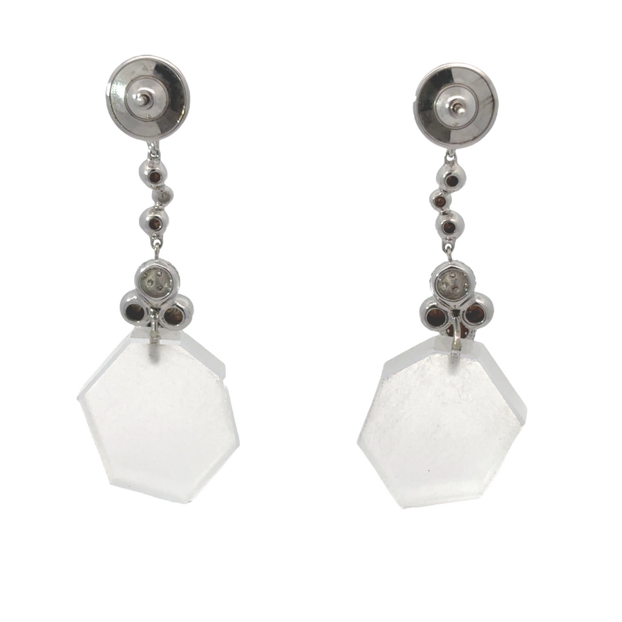 Side angle of white gold diamond earrings against neutral backdrop