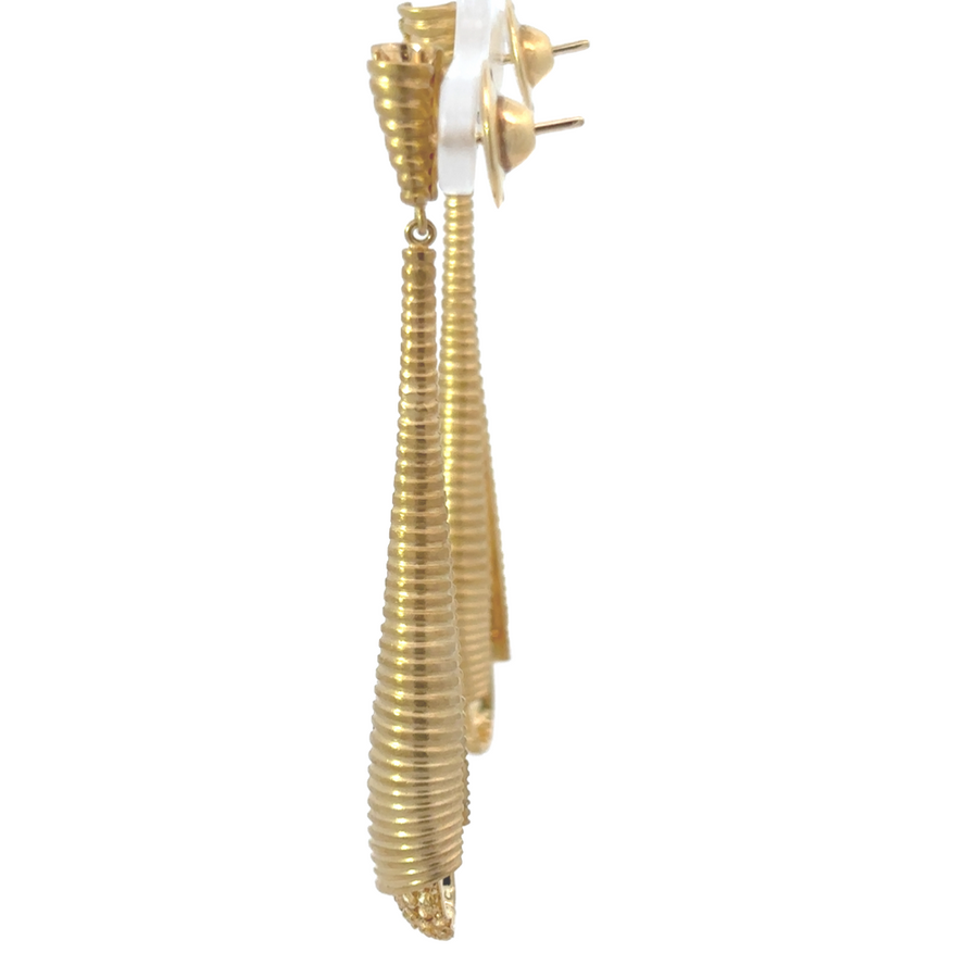 Side view of yellow gold diamond earrings against neutral background
