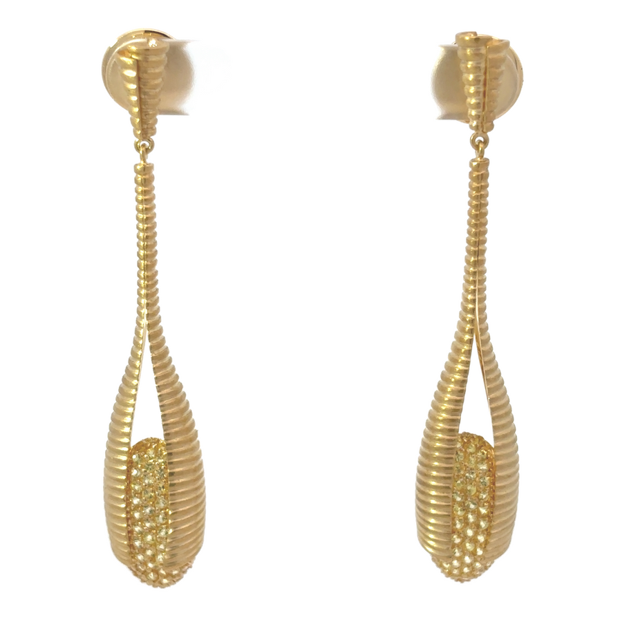 Pair of YG diamond earrings on a beige velvet surface